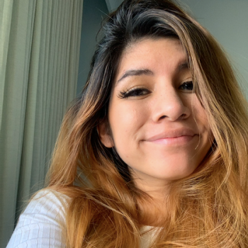 Paola Vidal-Espinoza is seen facing the camera with an off-white background.