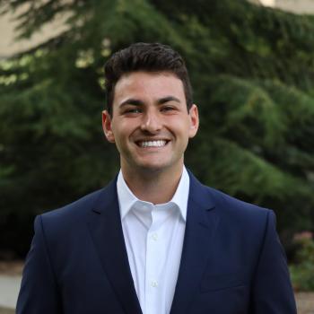 NHC member Brendan Reitman wearing a suit and smiling.