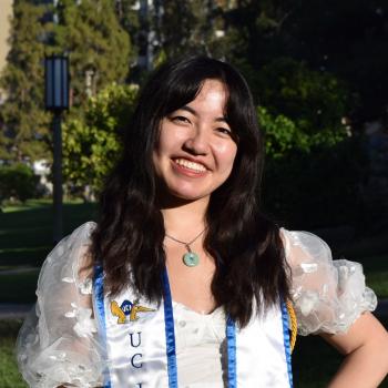 Sabrina Chiu stands in the middle of the frame, facing the camera and smiling.