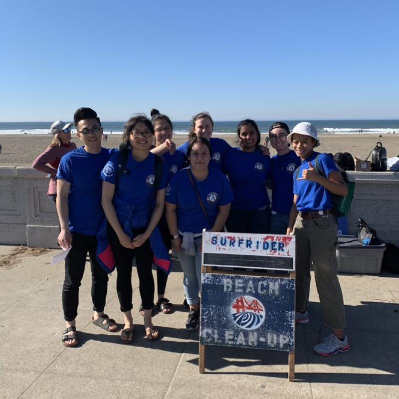 2019-2020 AmeriCorps members standing behind a beach cleanup sign. 