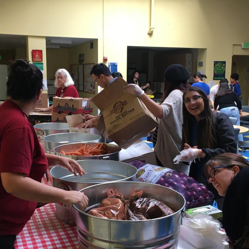 Neha Chhabra smiling as she prepares to unload a sack of onions into a bucket at the Curry Senior Center inaugural Food Pharmacy.