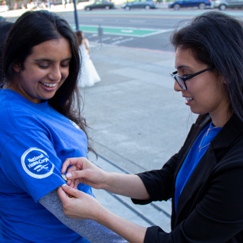 Shivani Bahl being pinned with the AmeriCorps pin by Program Director Nadia Majlessi.