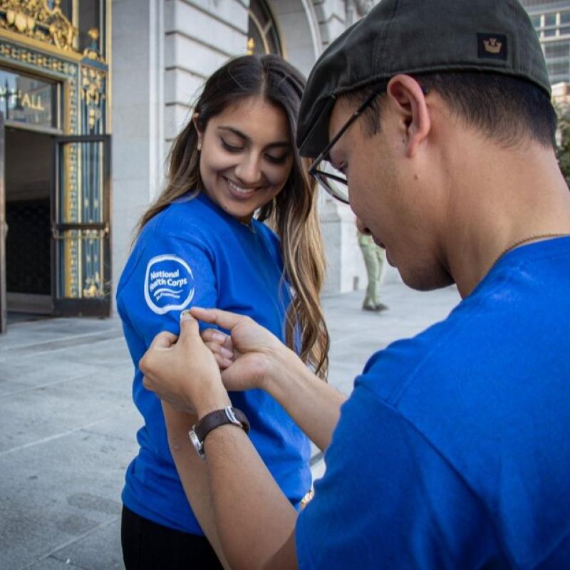 Neha Chhabra receiving her AmeriCorps pin in front of San Francisco City Hall.