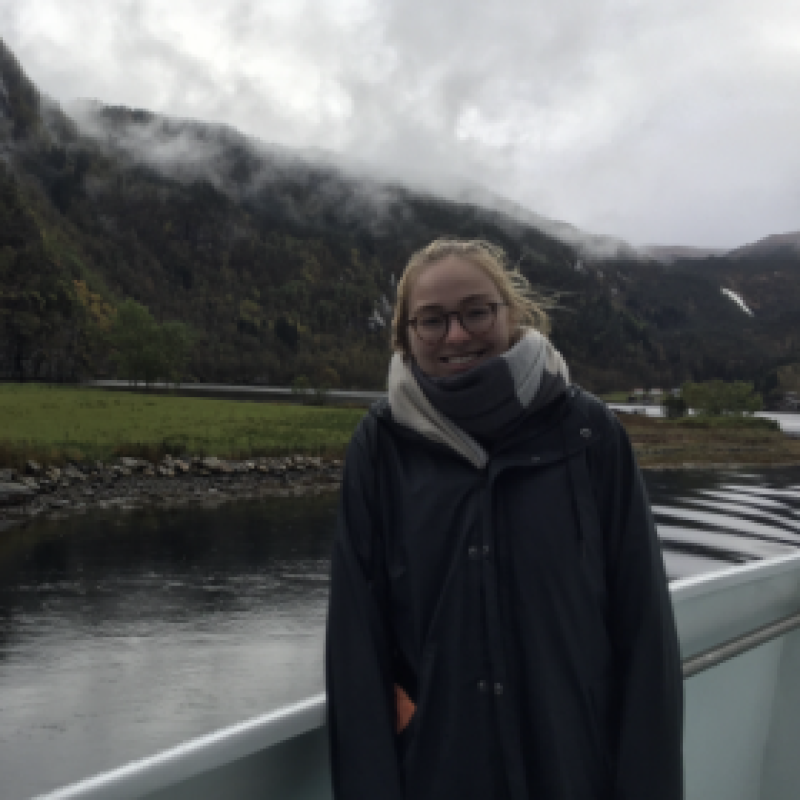 NHC PGH member Bethany smiling on a boat with mountains and water in the background