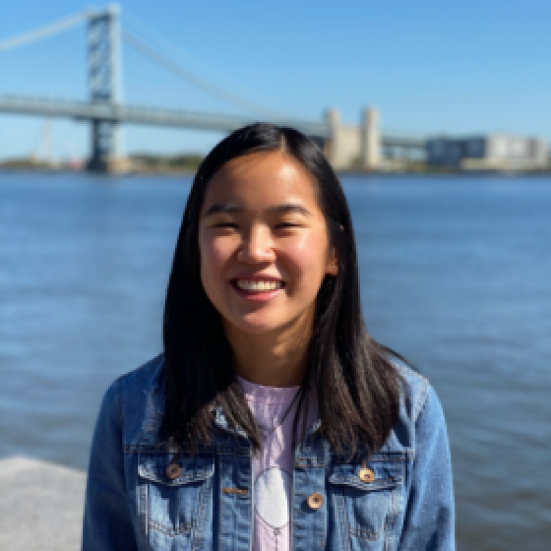 NHC PGH member Lily smiling on a sunny day with a bridge in the background