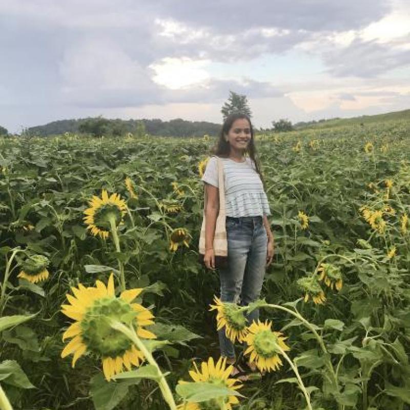 NHC PGH member Roosha smiling in a sunflower field