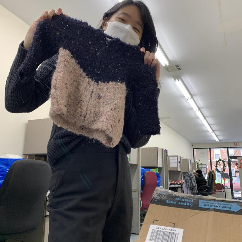 Soo holding baby clothes on site at CWHA.