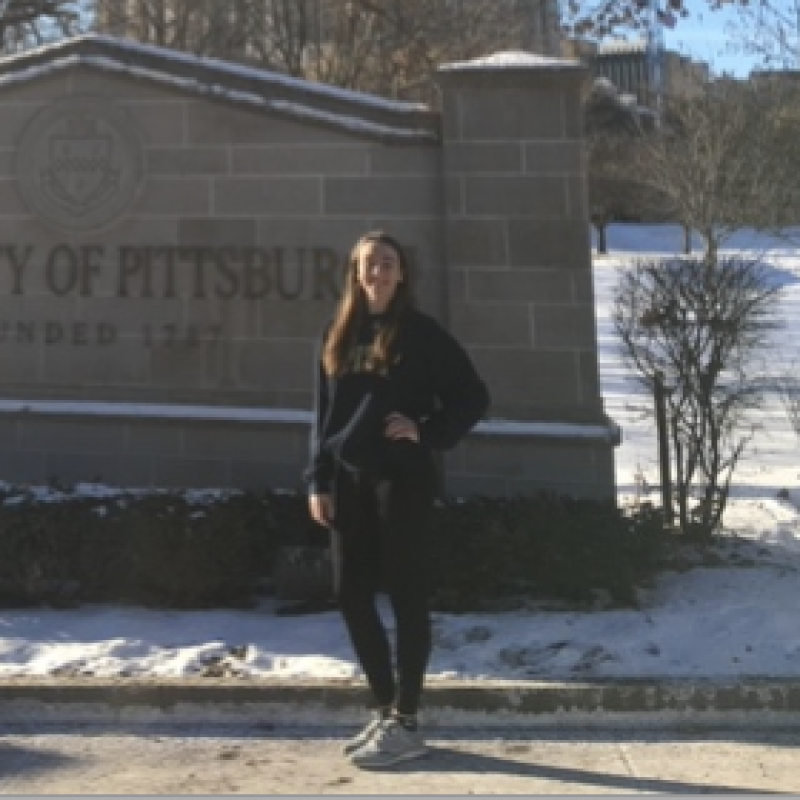 NHC PGH member Mary Margaret standing in front of a University of Pittsburgh sign