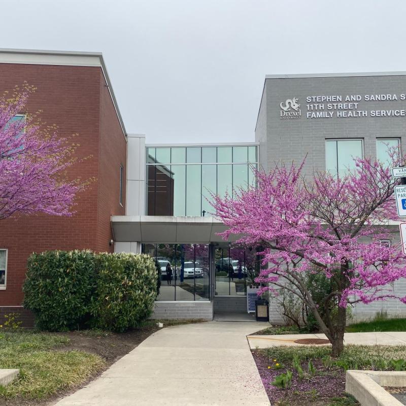 exterior of stephen and sandra sheller 11th street family health services center with two pink trees blooming 