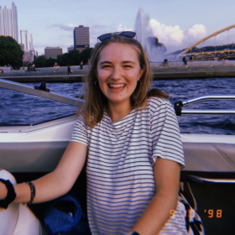 nhc pgh member lexi smiling on a boat with the pittsburgh skyline