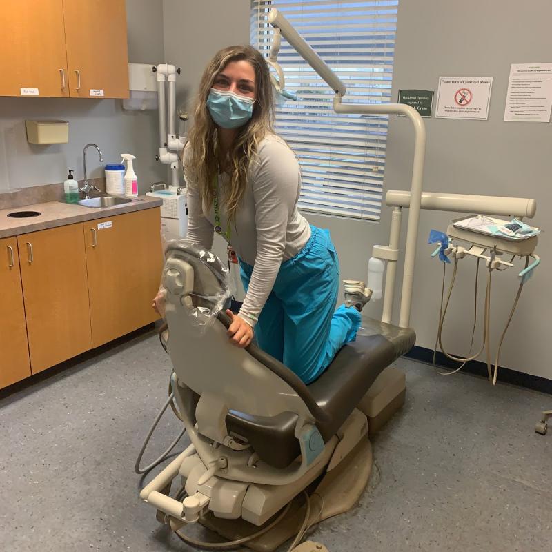 Cassidy kneeling on the dental chair