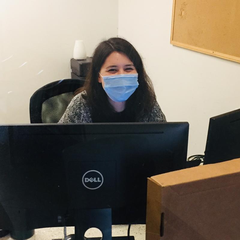Charlotte Kishi sitting behind a desk, with two computer monitors in front of her.