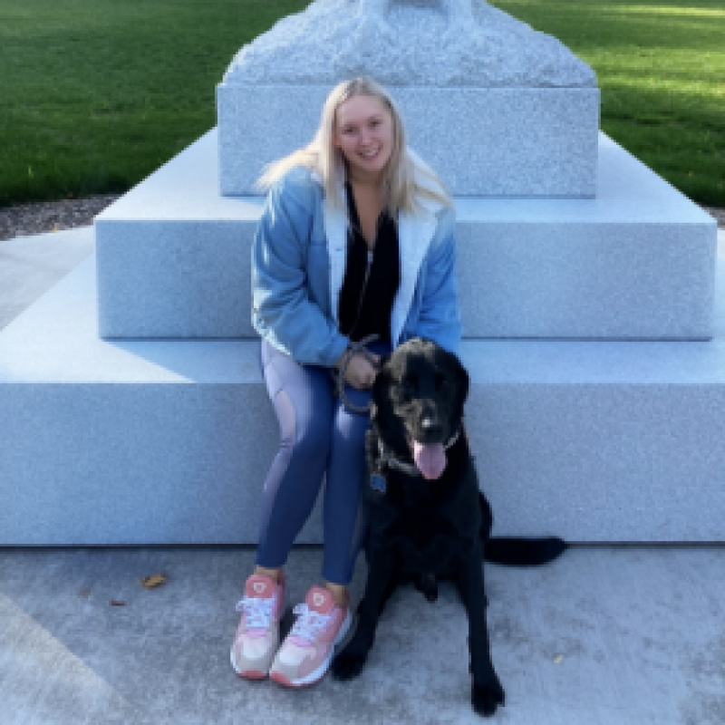 NHC PGH member Laurel smiling in front of a statue with her dog