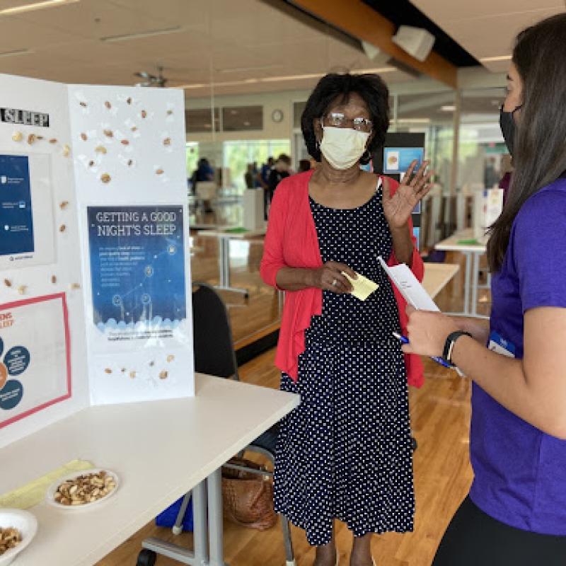 Carly listening to one of the senior’s science fair  presentations on the connection between sleep and brain health.