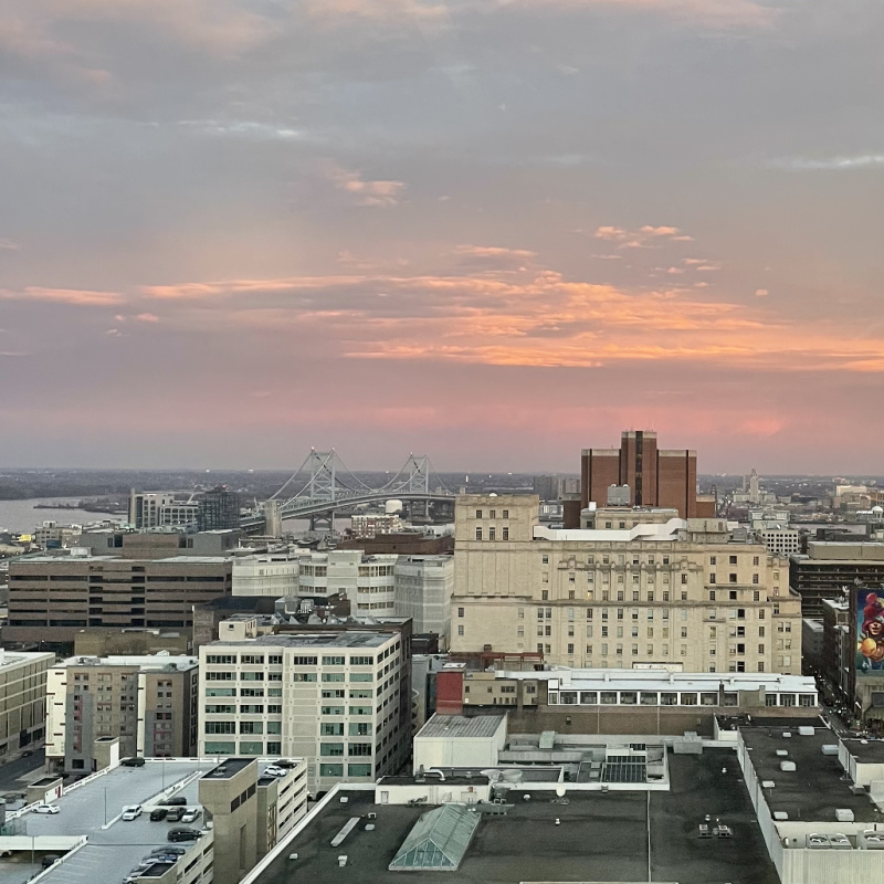 A sunset with buildings and the ben franklin bridge in the foreground