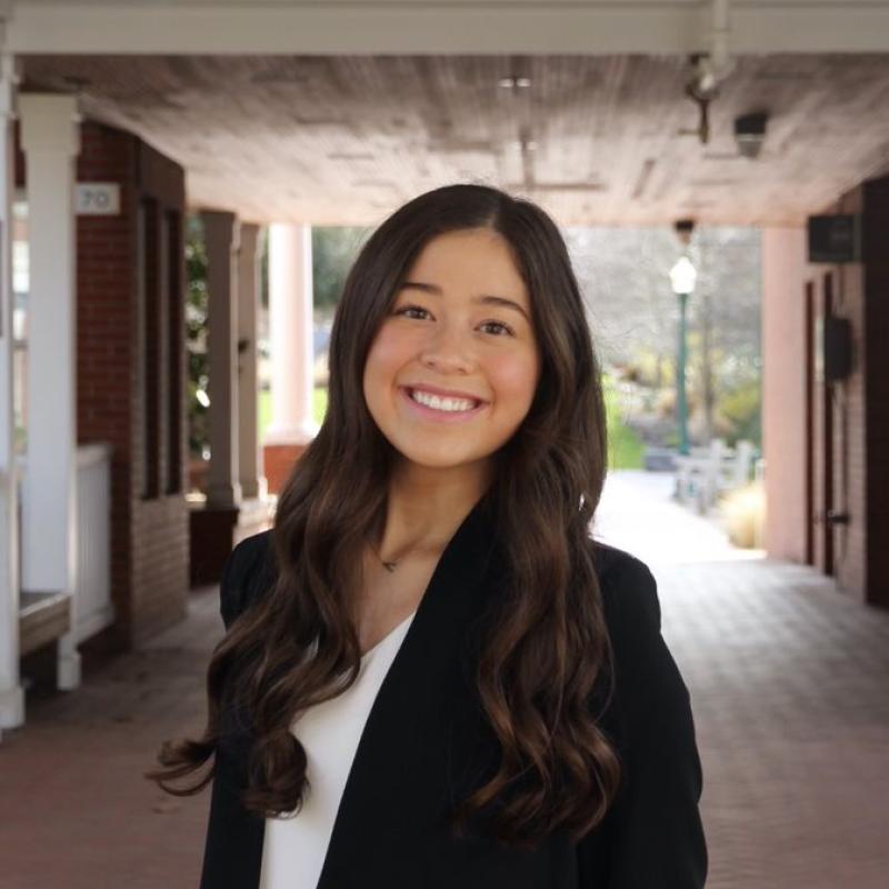 Aly Sato is seen facing the camera in the middle of the frame, smiling towards the camera. 