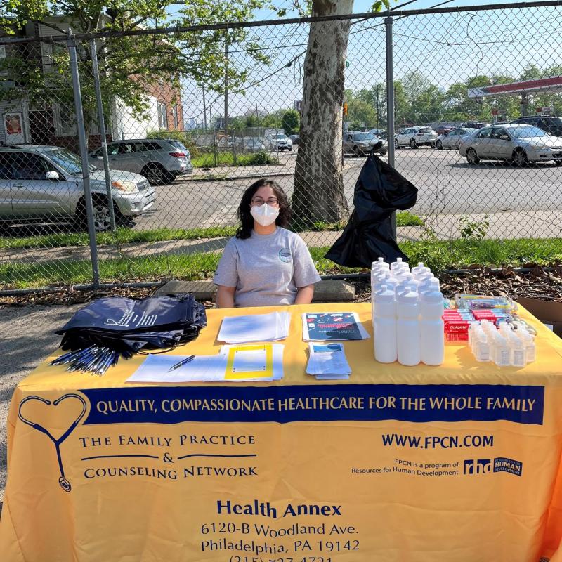 Amal sitting a table handing out resources for community members