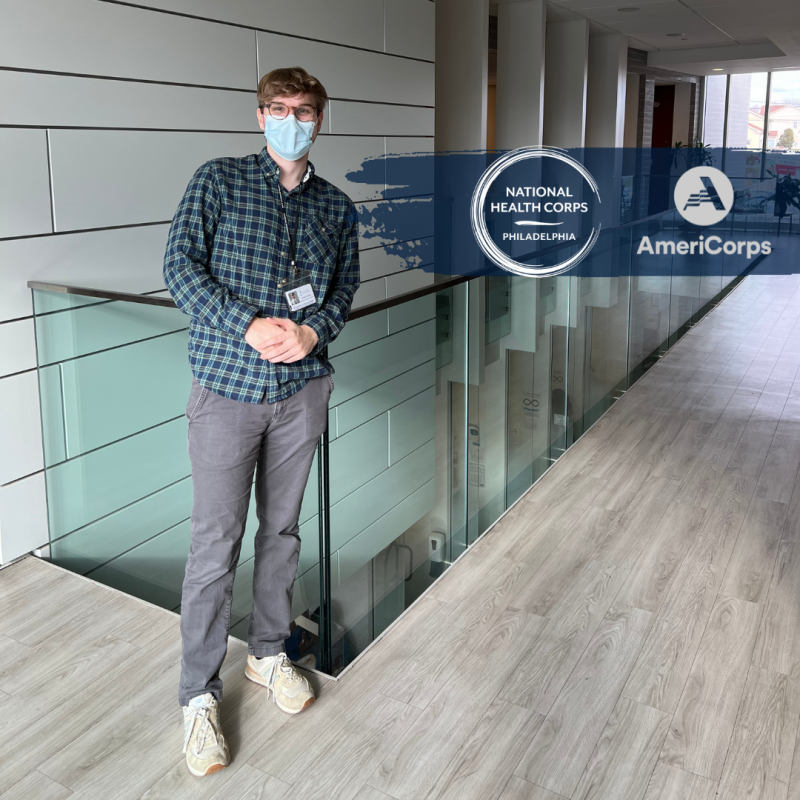 Corey standing near a banister with the NHC and AmeriCorps logos added in next to him