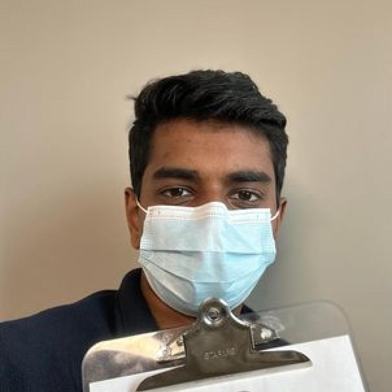 Sai is seen facing the camera and holding a clipboard with the HealthRIGHT 360 logo at the top of the page. 