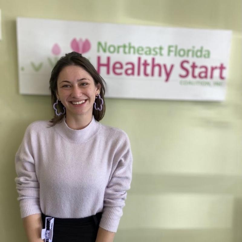 Philine standing in front of host site sign