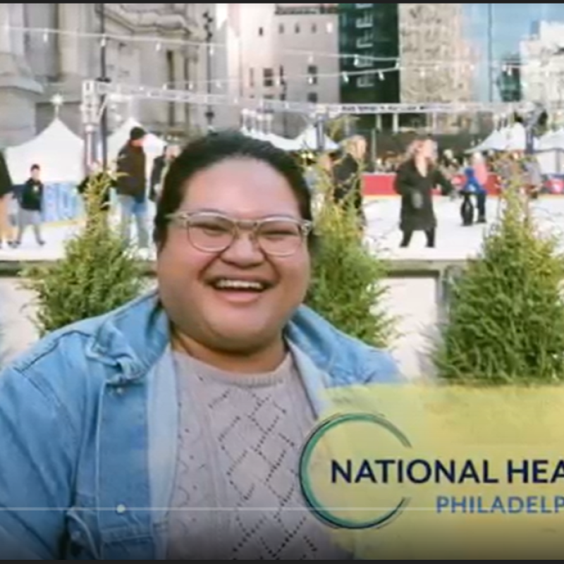 Johanna smiling in front of an ice rink. The NHC Philadelphia logo is in the bottom right corner.