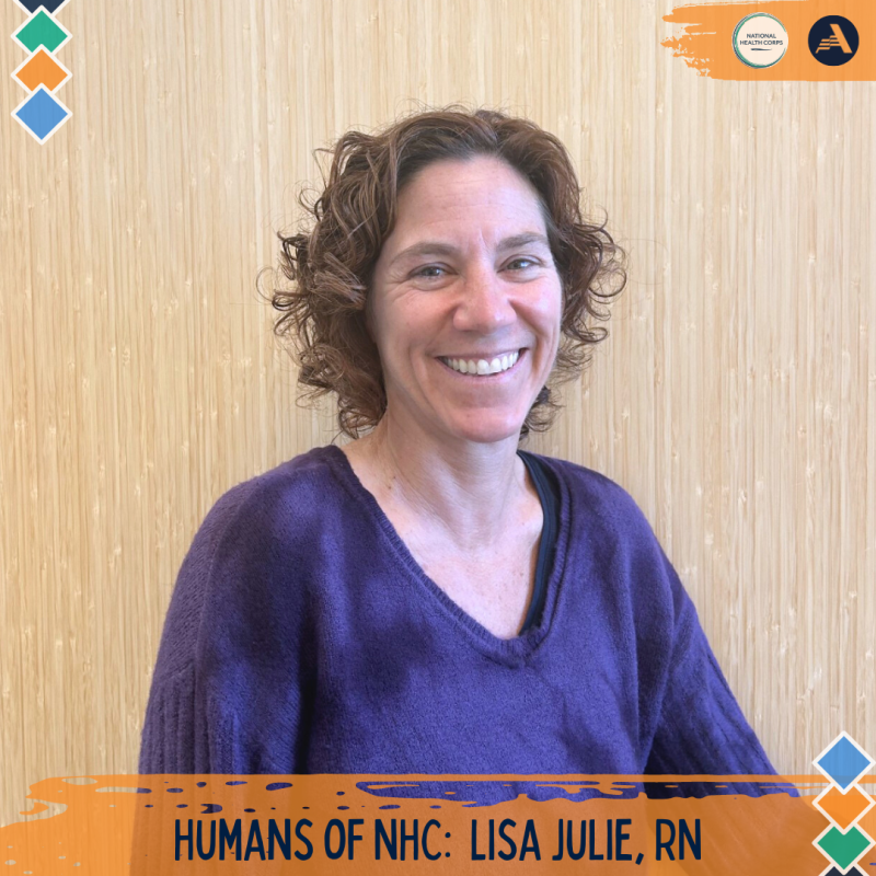 Lisa Julie is standing in the center of the frame, facing the camera and smiling. 