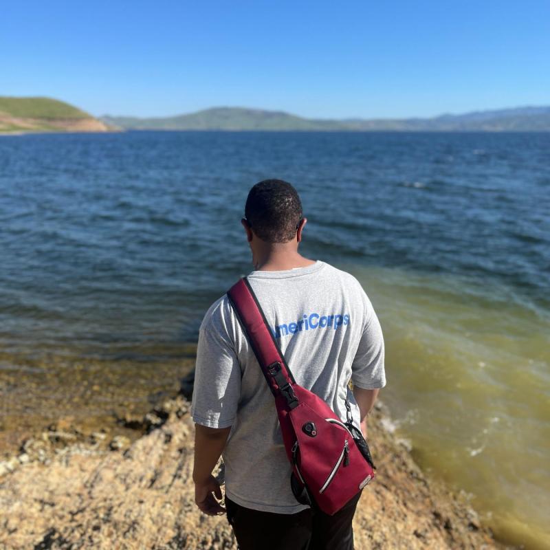 Cameron with AmeriCorps shirt over reservoir