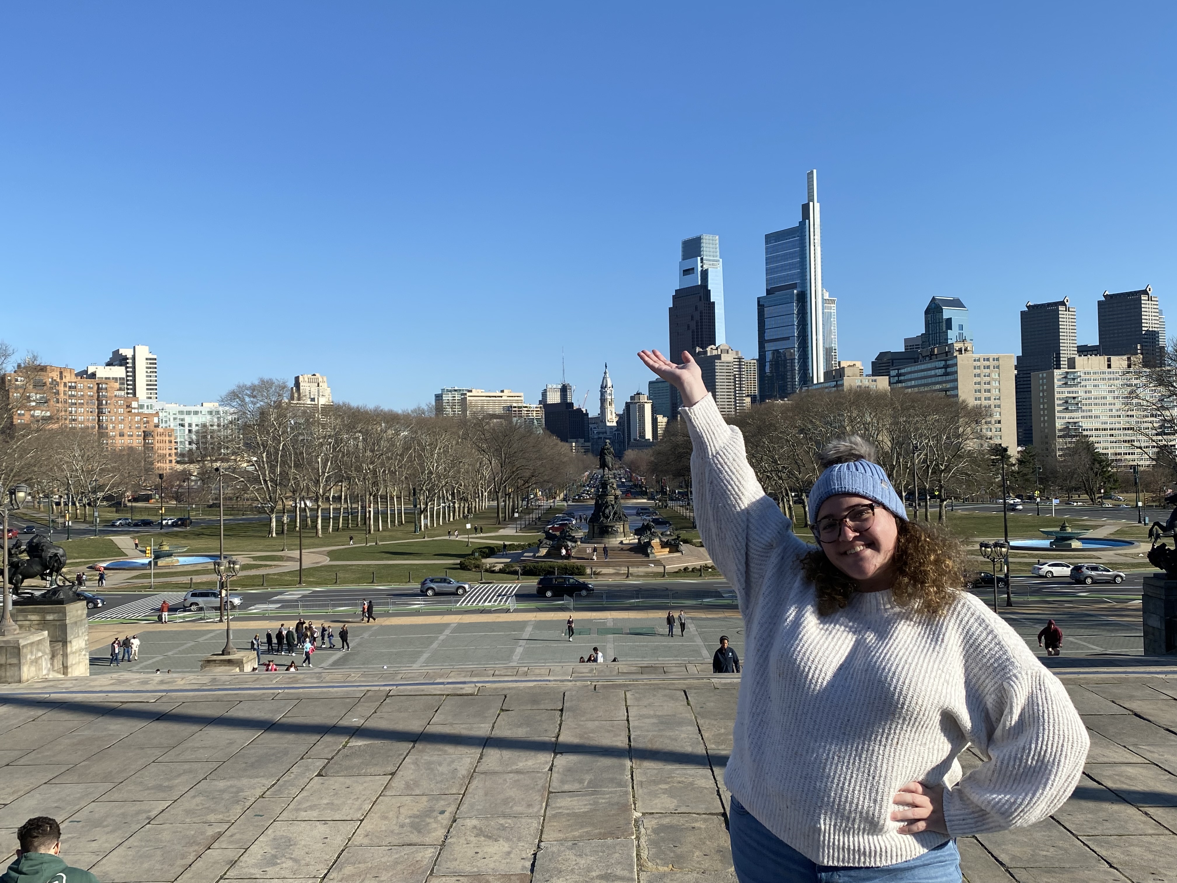 Emily standing on the Philadelphia Art Museum steps with the city skyline in the background